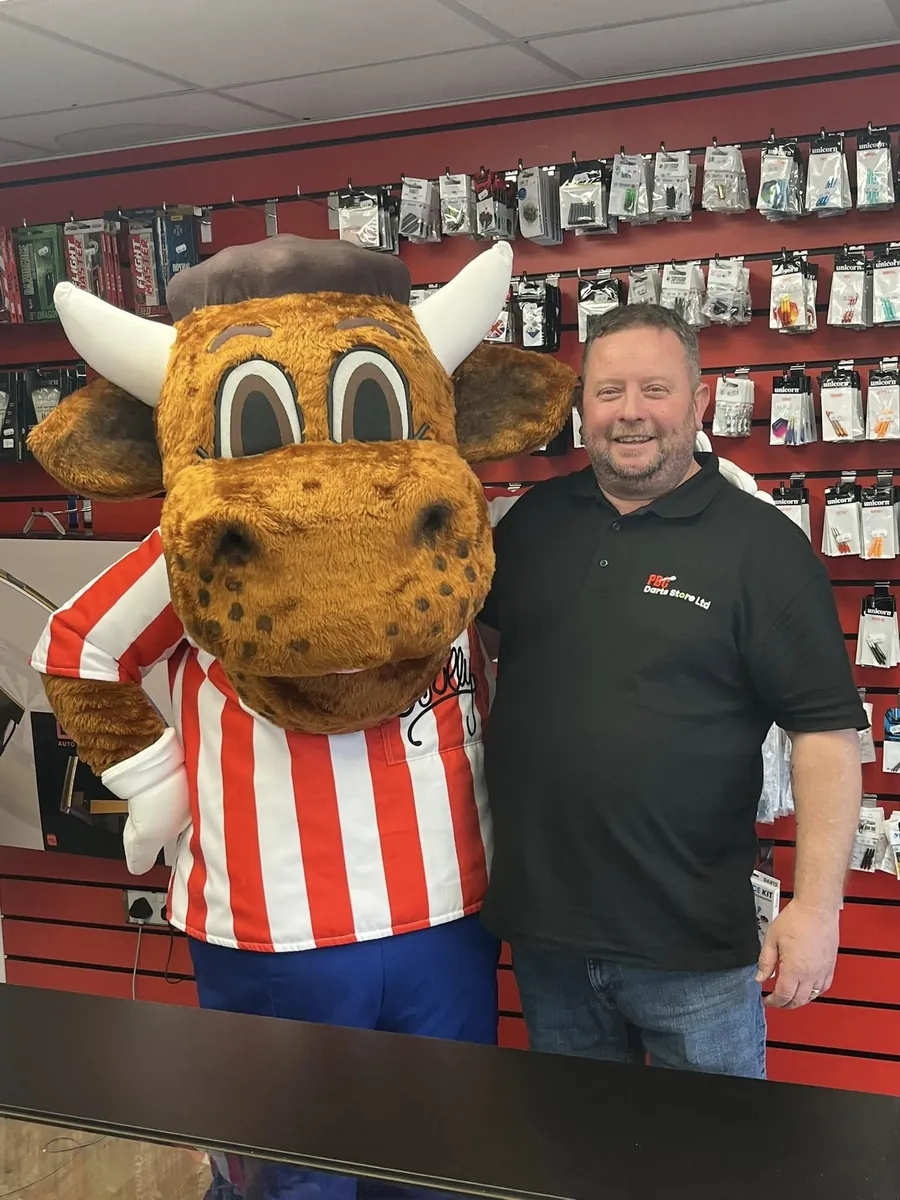 Andy behind the counter with Bully, in front of the wall of flights and shafts